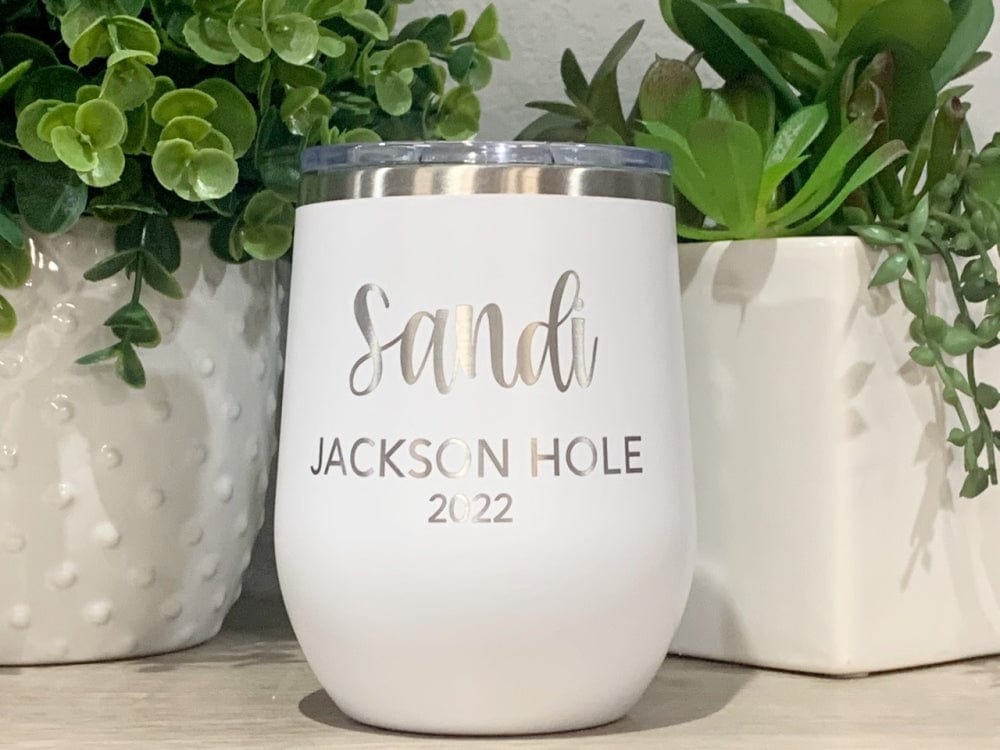White wine tumbler with the name Sandy, destination of Jackson Hole and year 2022 text, surrounded by plants.