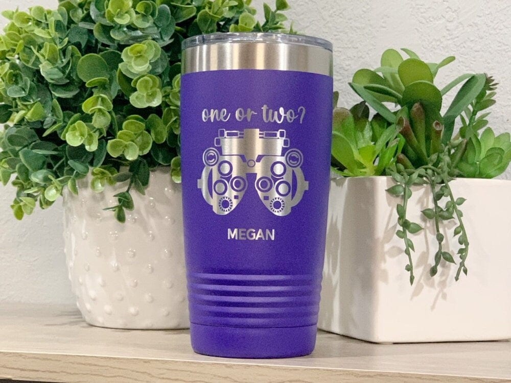 Purple 20oz tumbler engraved with the words one or two?, phoropter personalized with name in front of two plants on shelf