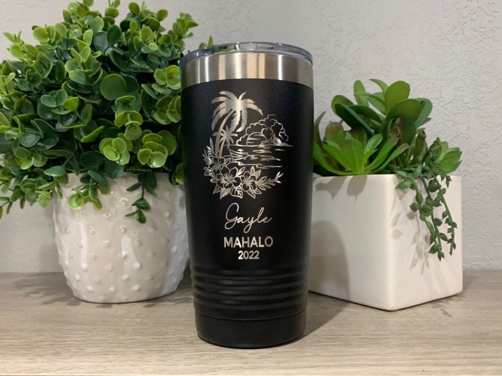 laser engraved tumbler with ocean design that has water, sun, mountain, boat, flowers etc. personalized with name, vacation destination and year