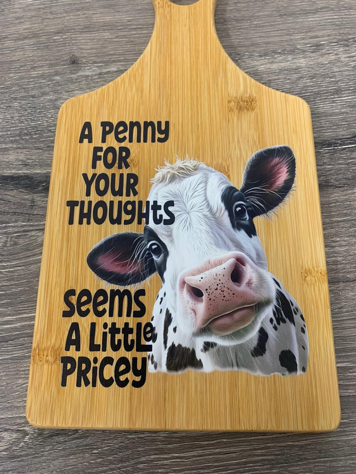 Decorative bamboo paddle board with sarcastic lettering and the words “A Penny for Your Thoughts Seems a Little Pricey”.