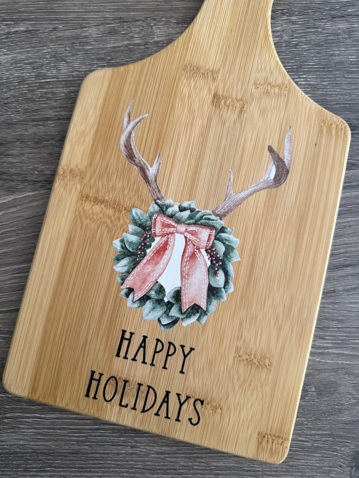Decorative bamboo paddle board with antler wreath with a bow.