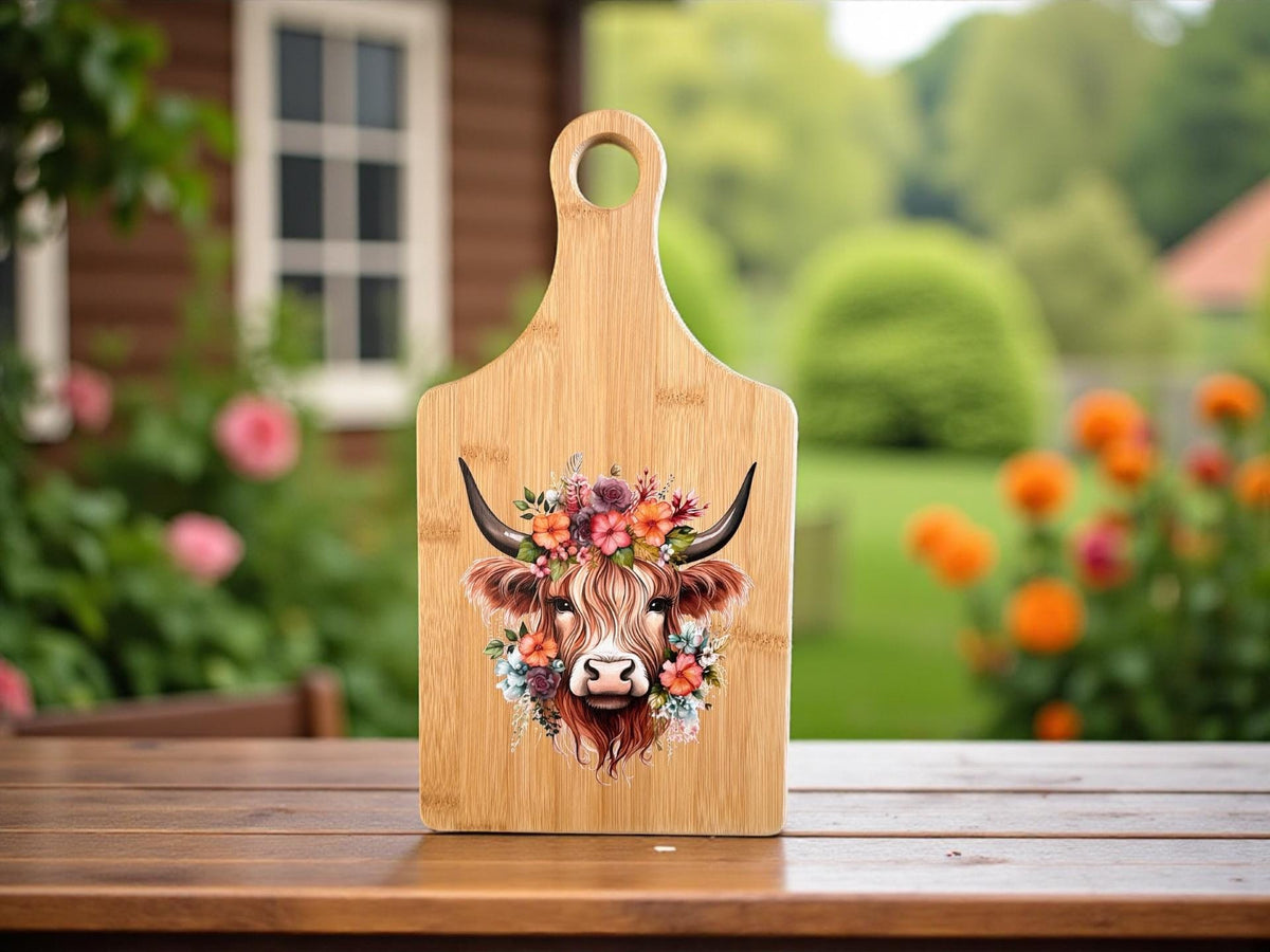 Decorative bamboo paddle board with Highland cow surrounded by flowers.