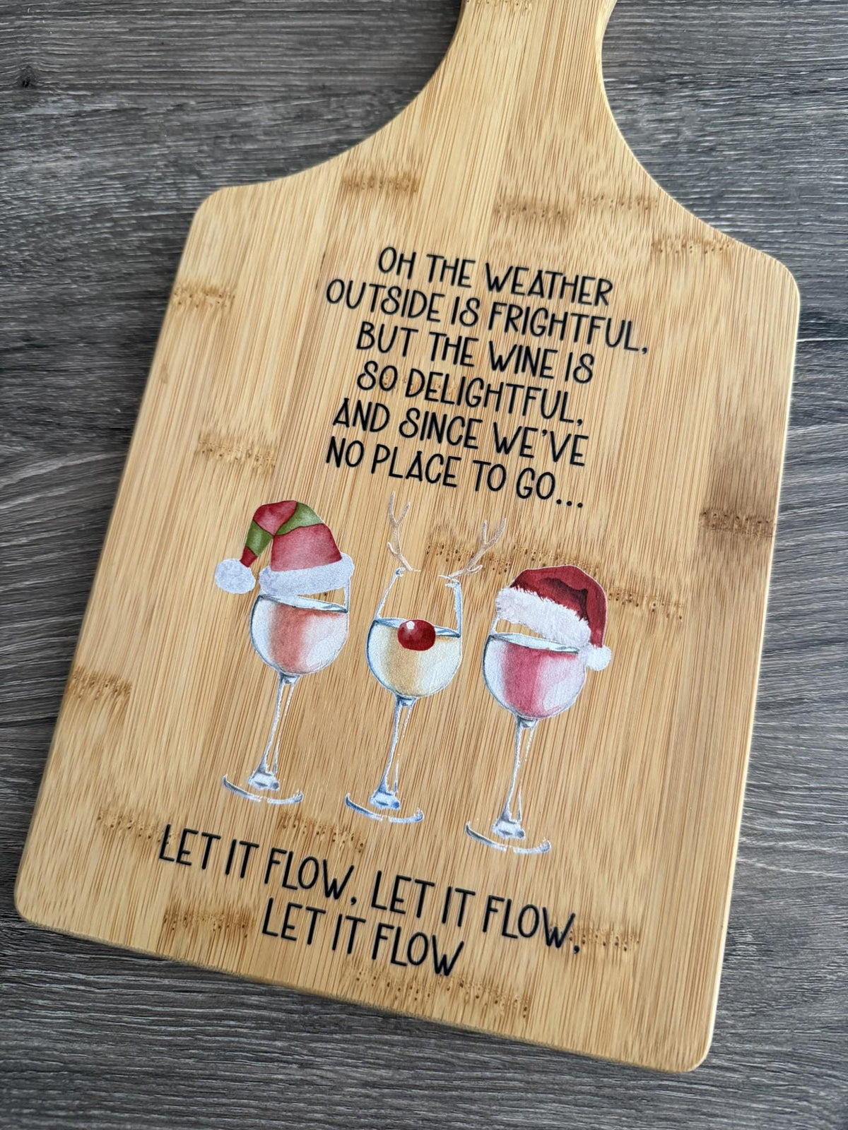 Decorative bamboo paddle board with Christmas wine-themed artwork and the words “Let It Flow Christmas Wine”.