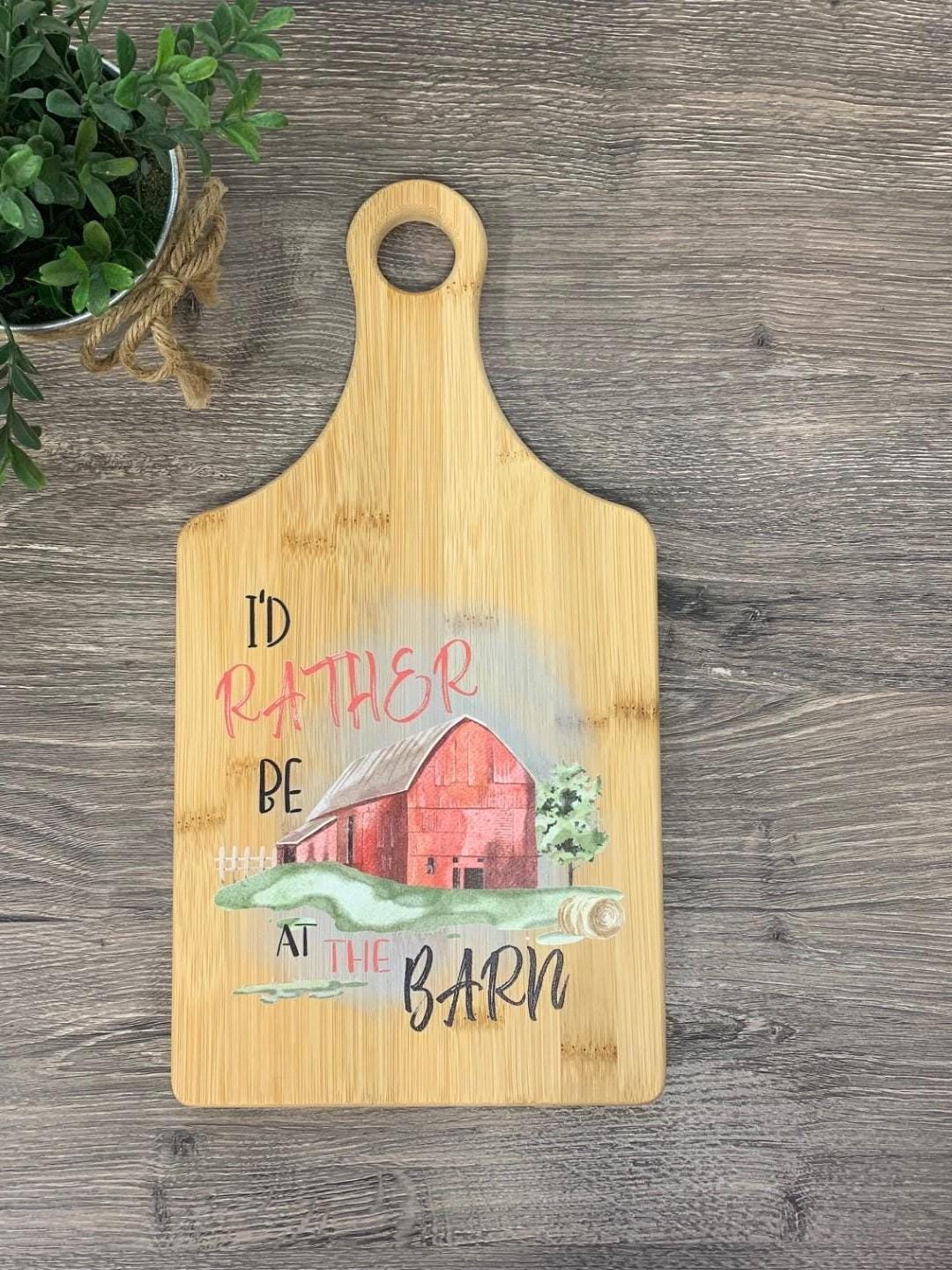 Decorative bamboo paddle board with rustic barn-themed lettering and the words “I'd Rather Be at the Barn”.