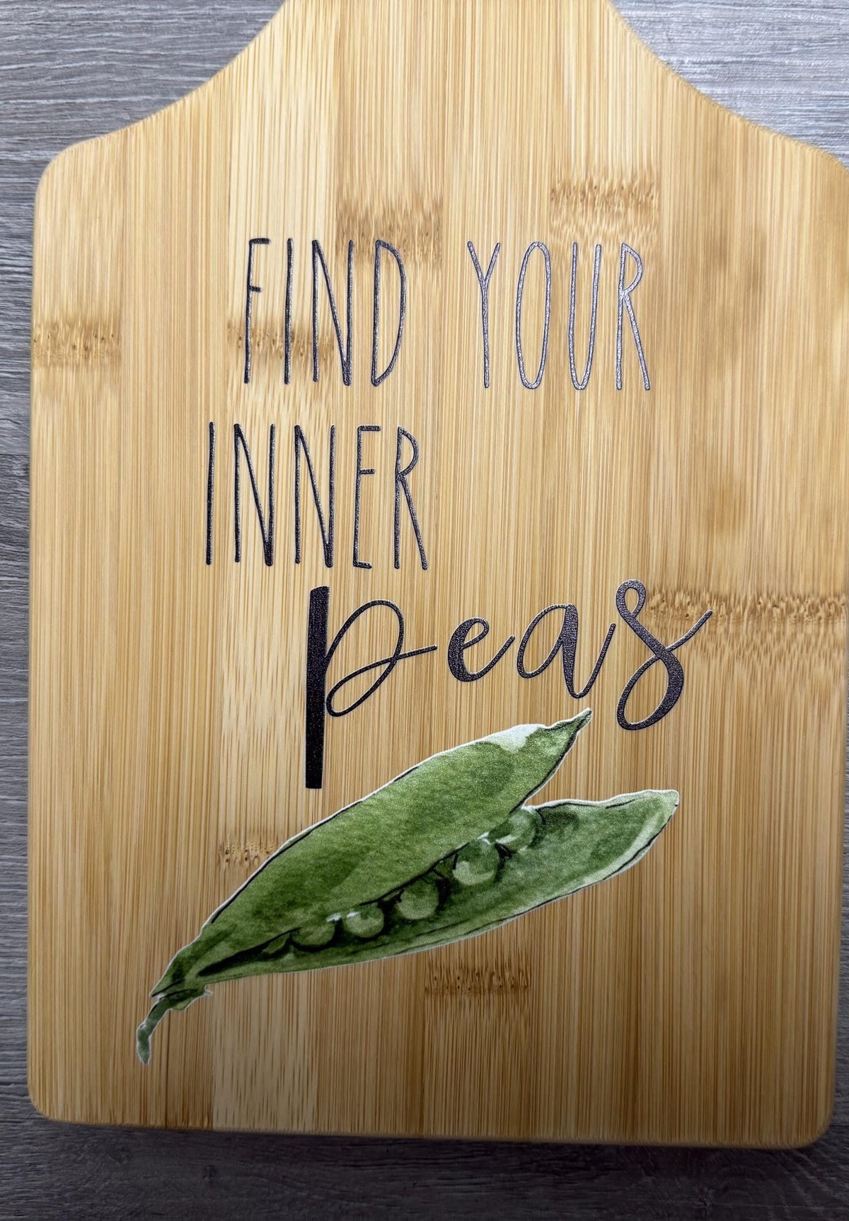 Decorative bamboo paddle board with peas illustration and the words “Find Your Inner Peas”.