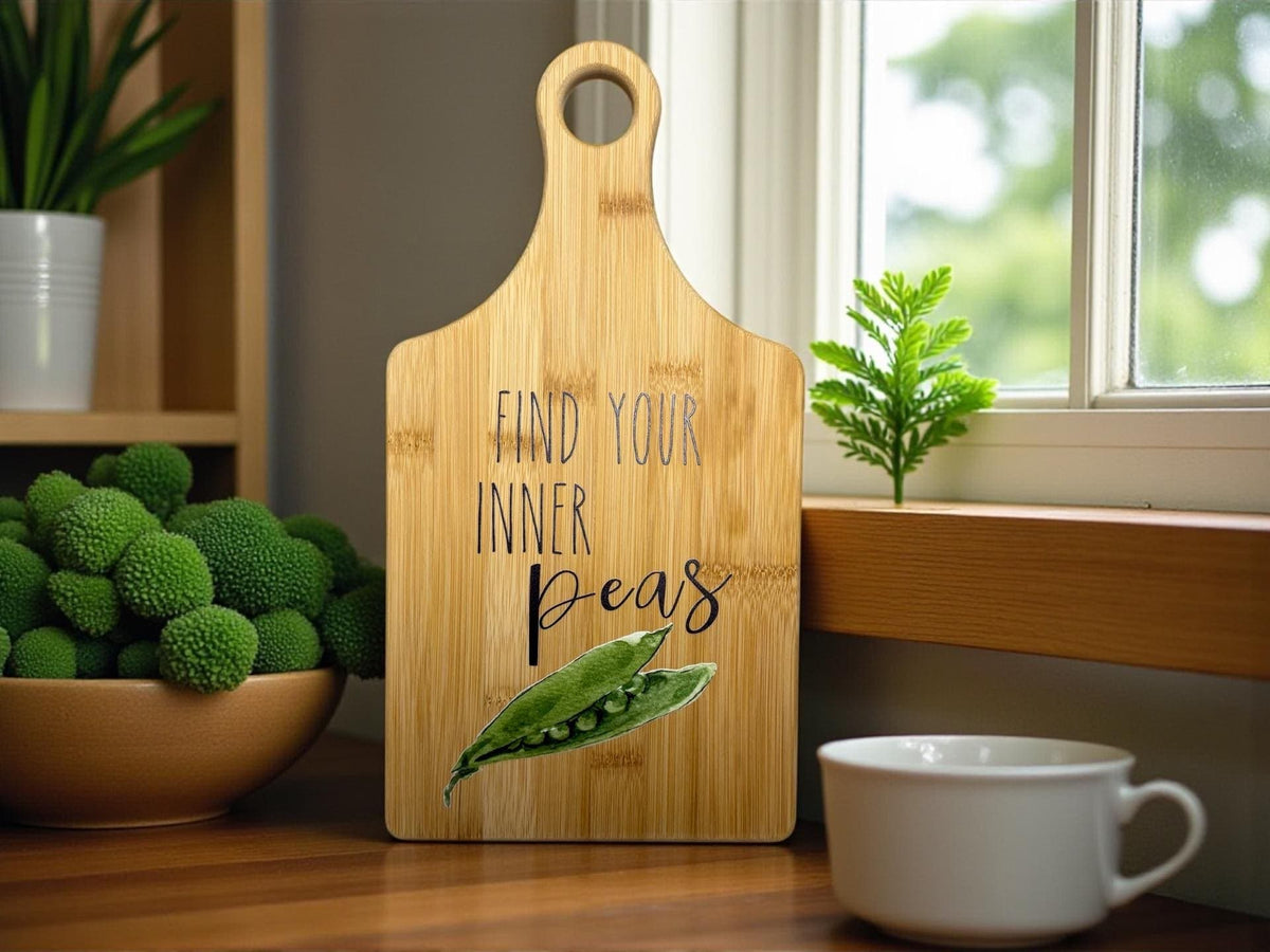 Decorative bamboo paddle board with peas illustration and the words “Find Your Inner Peas”.