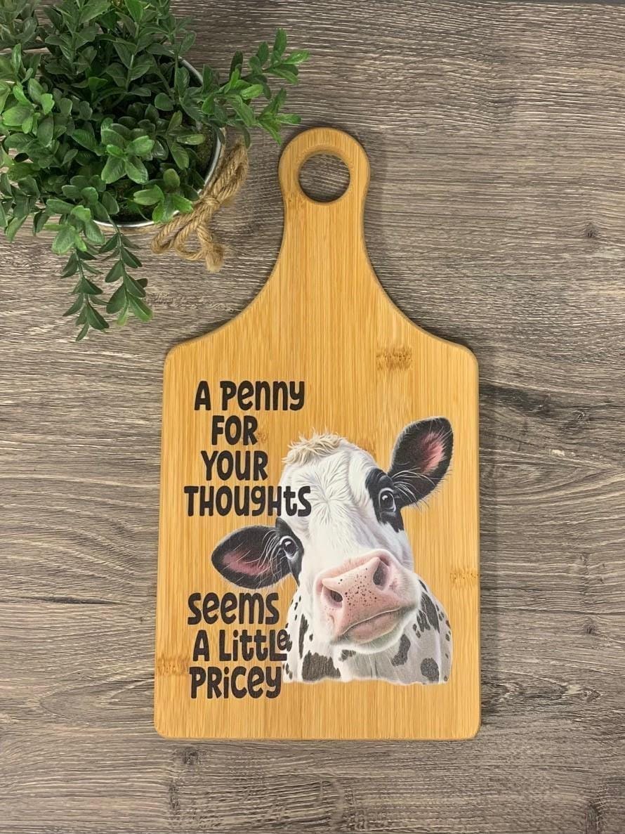 Decorative bamboo paddle board with sarcastic lettering and the words “A Penny for Your Thoughts Seems a Little Pricey”.