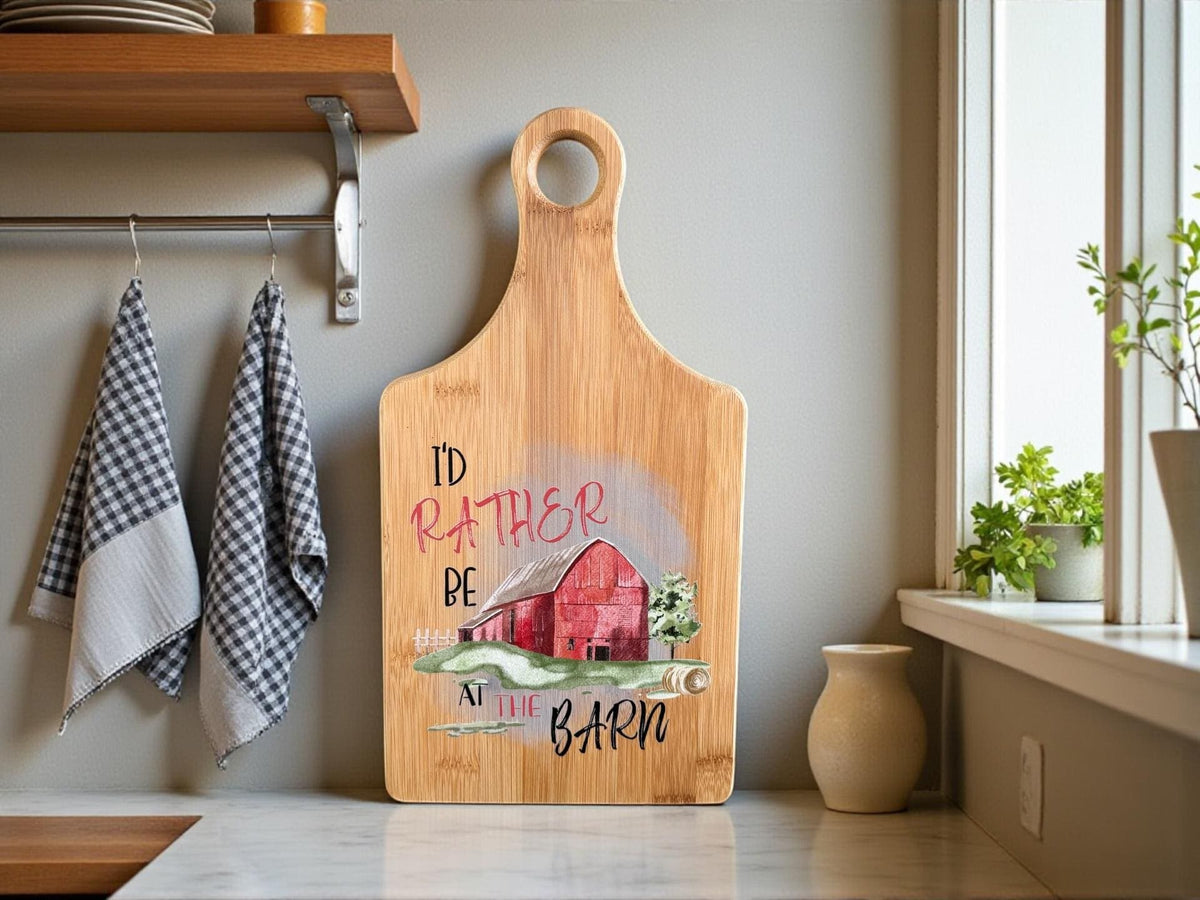 Decorative bamboo paddle board with rustic barn-themed lettering and the words “I'd Rather Be at the Barn”.