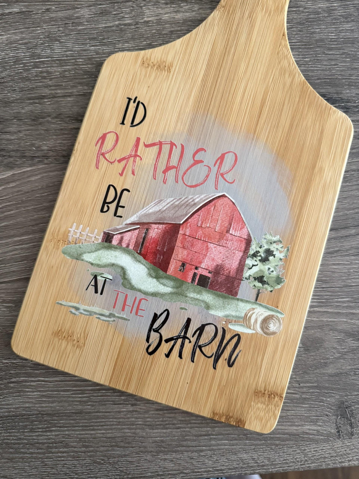 Decorative bamboo paddle board with rustic barn-themed lettering and the words “I'd Rather Be at the Barn”.