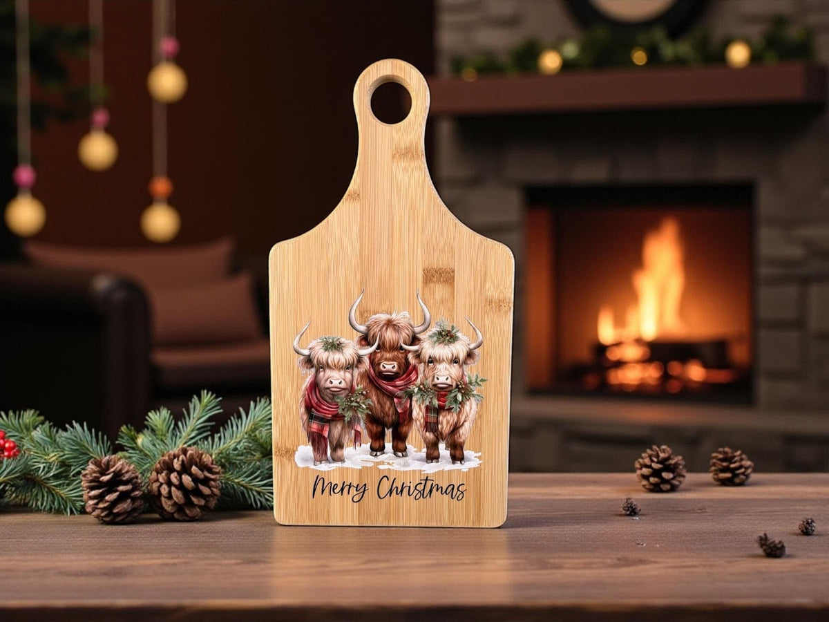 Decorative bamboo paddle board with three festive Highland cows.