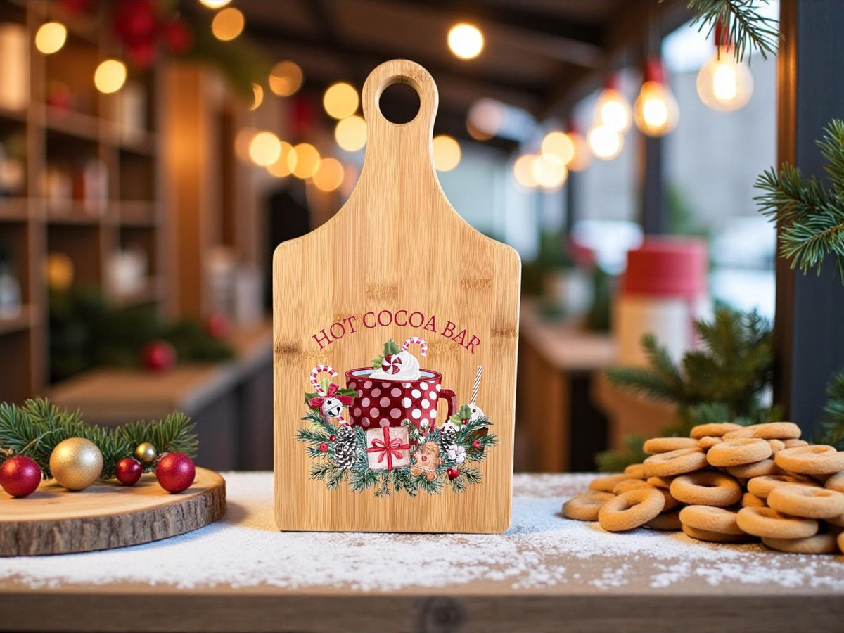 Decorative bamboo paddle board with hot cocoa mug with candy canes and the words “Hot Cocoa Bar”.