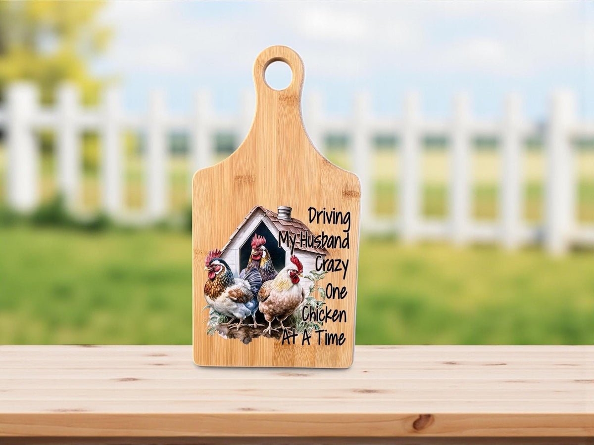 Decorative bamboo paddle board with chicken illustration and the words “Driving My Husband Crazy One Chicken at a Time”.