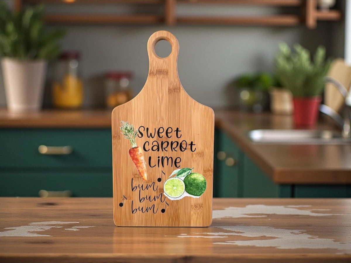 Decorative bamboo paddle board with carrot and lime artwork and the words “Sweet Carrot Lime”.