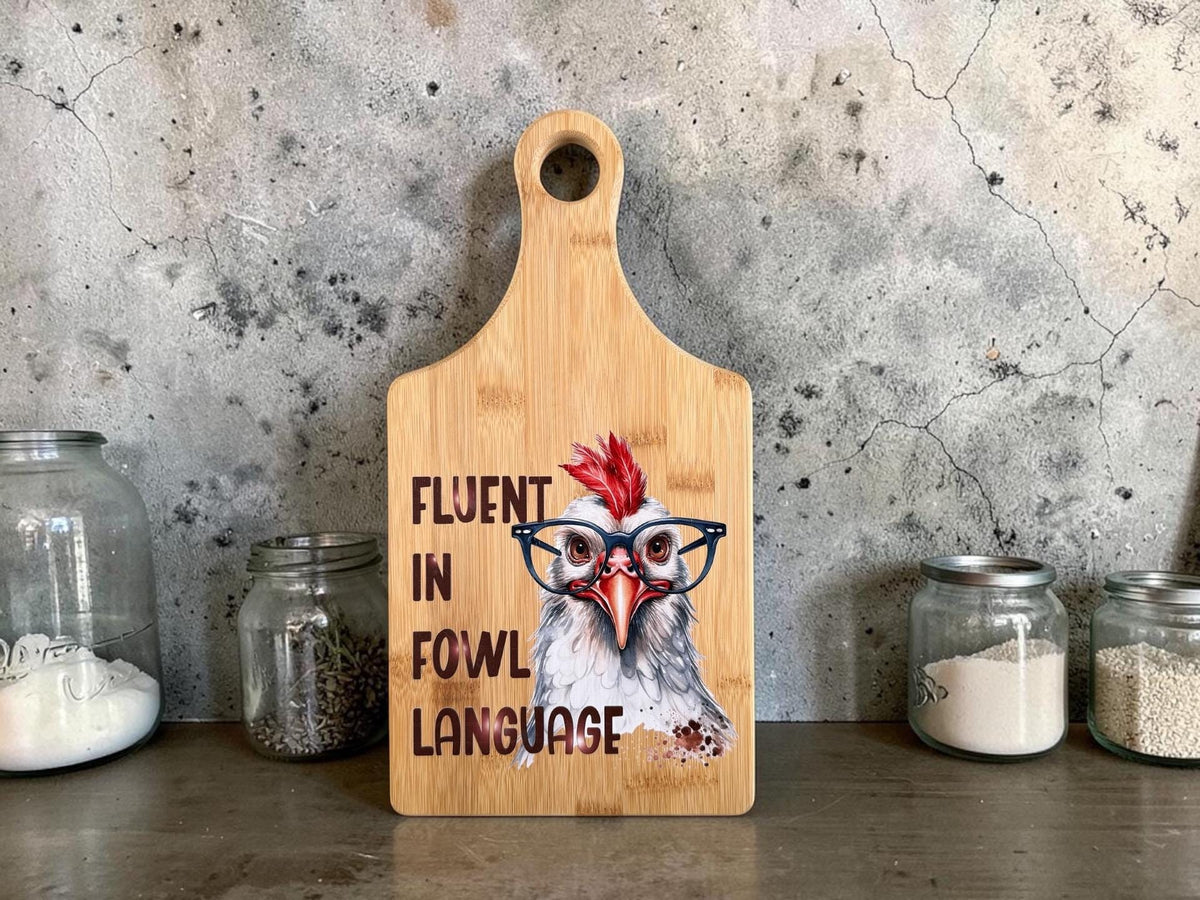 Decorative bamboo paddle board with chicken illustration and the words “Fluent in Fowl Language”.