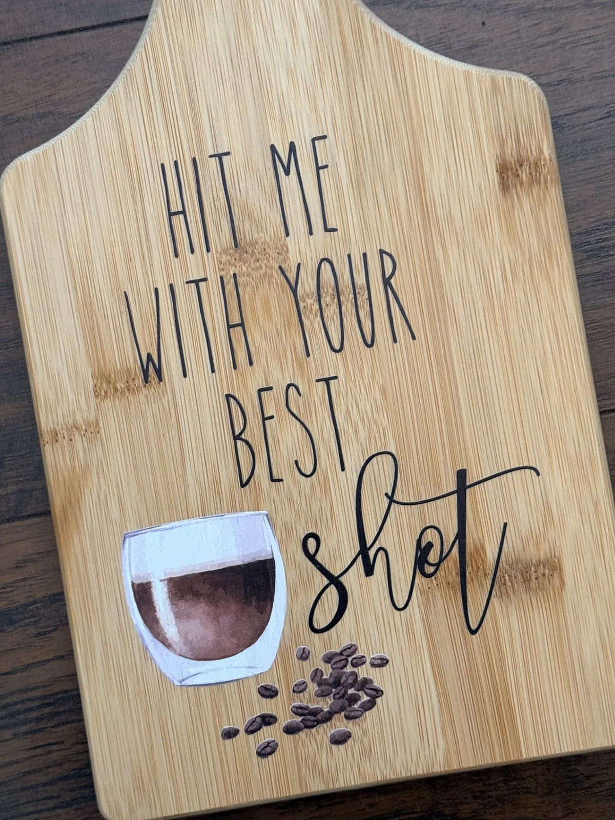 Decorative bamboo paddle board with coffee cup and the words “Hit Me With Your Best Shot”.