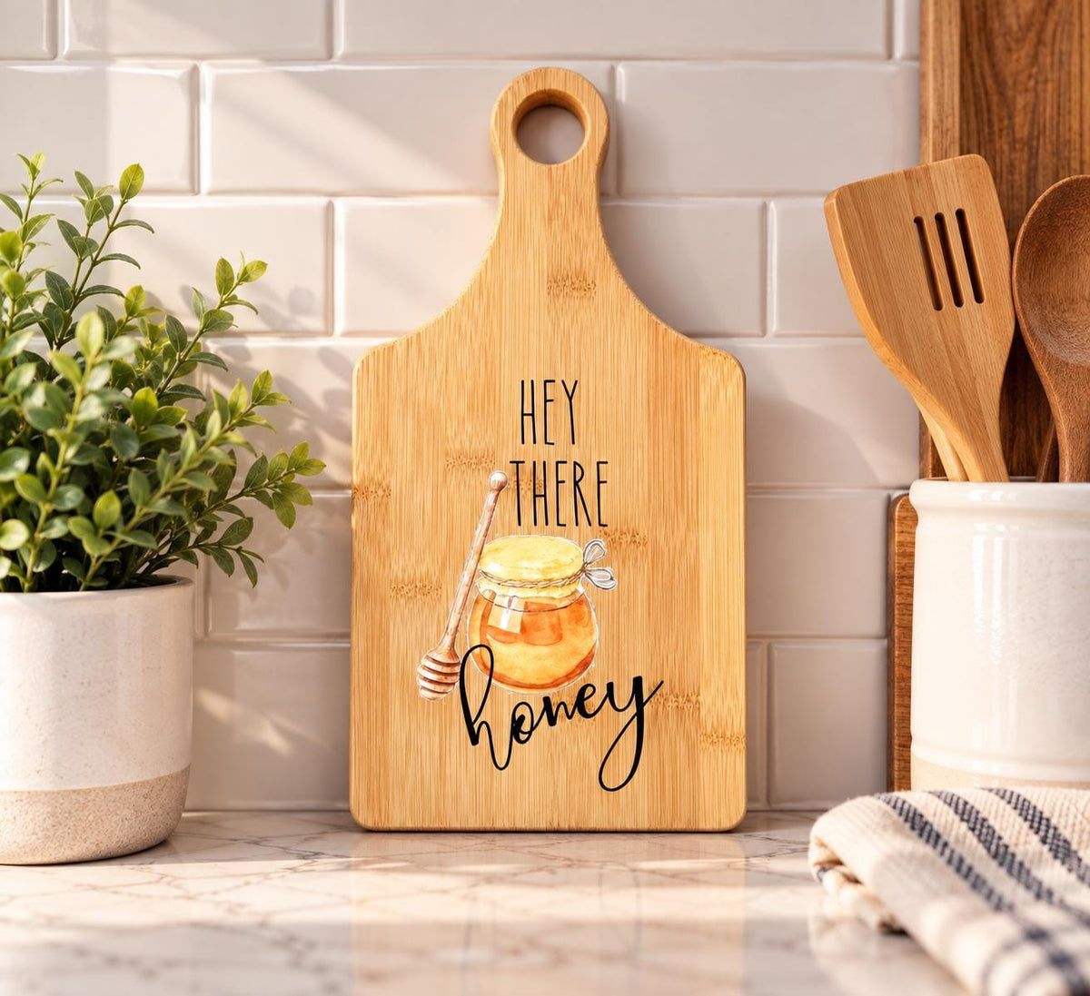 Decorative bamboo paddle board with honey bee illustration and the words “Hey There Honey”.