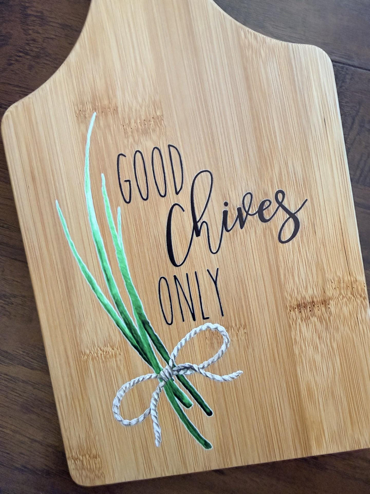 Decorative bamboo paddle board with chive herb illustration and the words “Good Chives Only”.