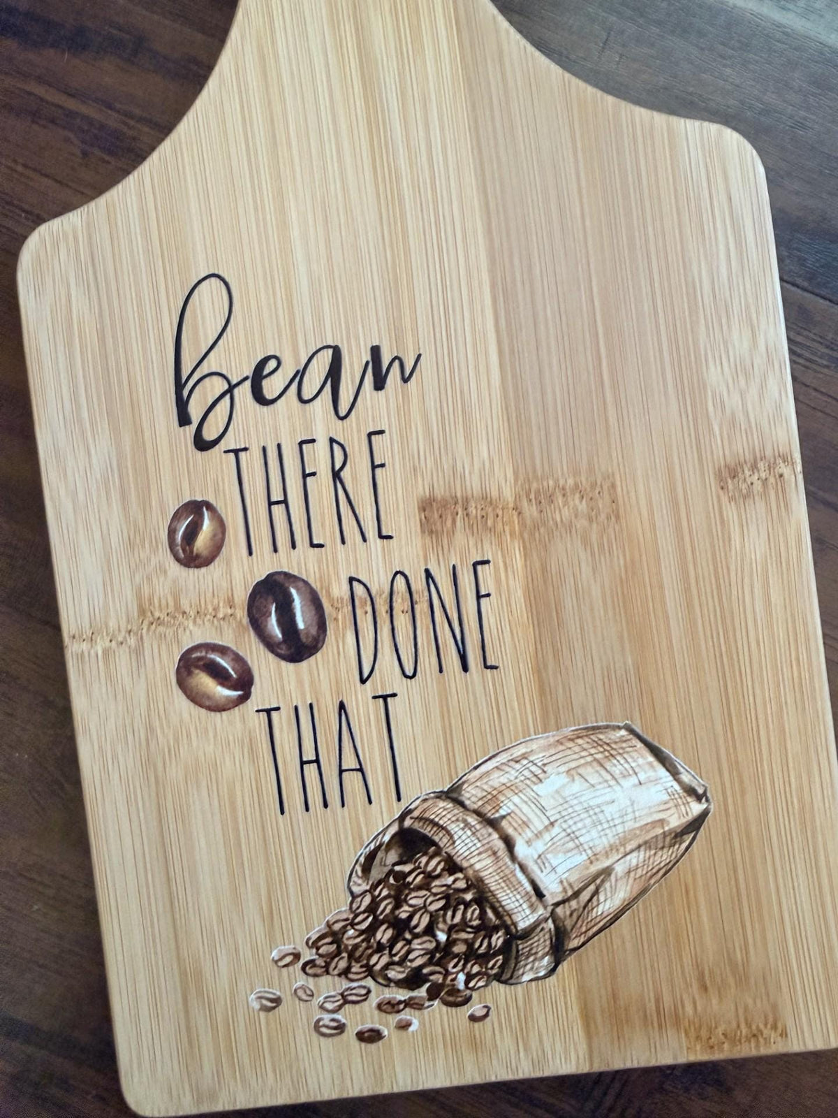 Decorative bamboo paddle board with coffee beans and the words “Bean There, Done That”.