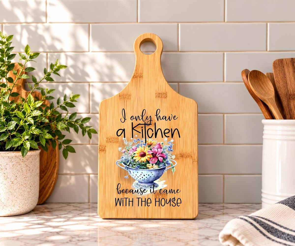 Decorative bamboo paddle board with humorous lettering and the words “I Only Have a Kitchen Because It Came With the House”.