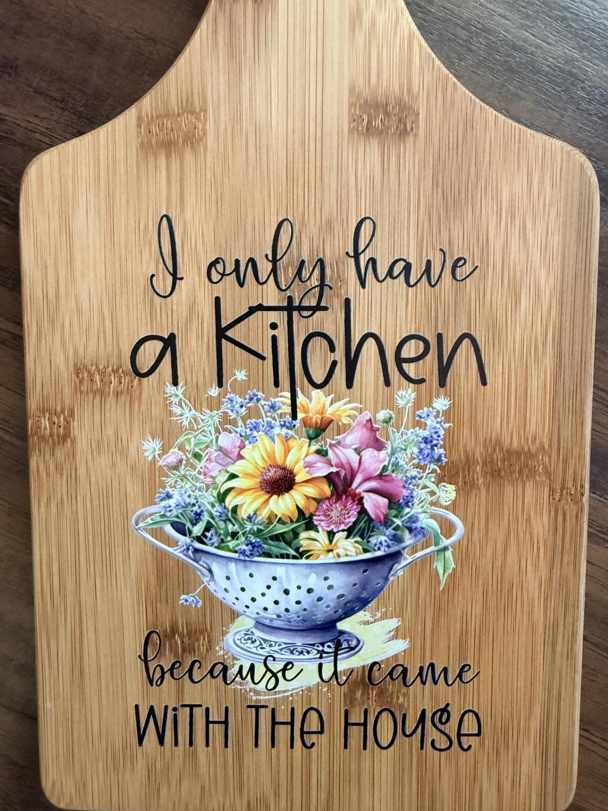 Decorative bamboo paddle board with humorous lettering and the words “I Only Have a Kitchen Because It Came With the House”.
