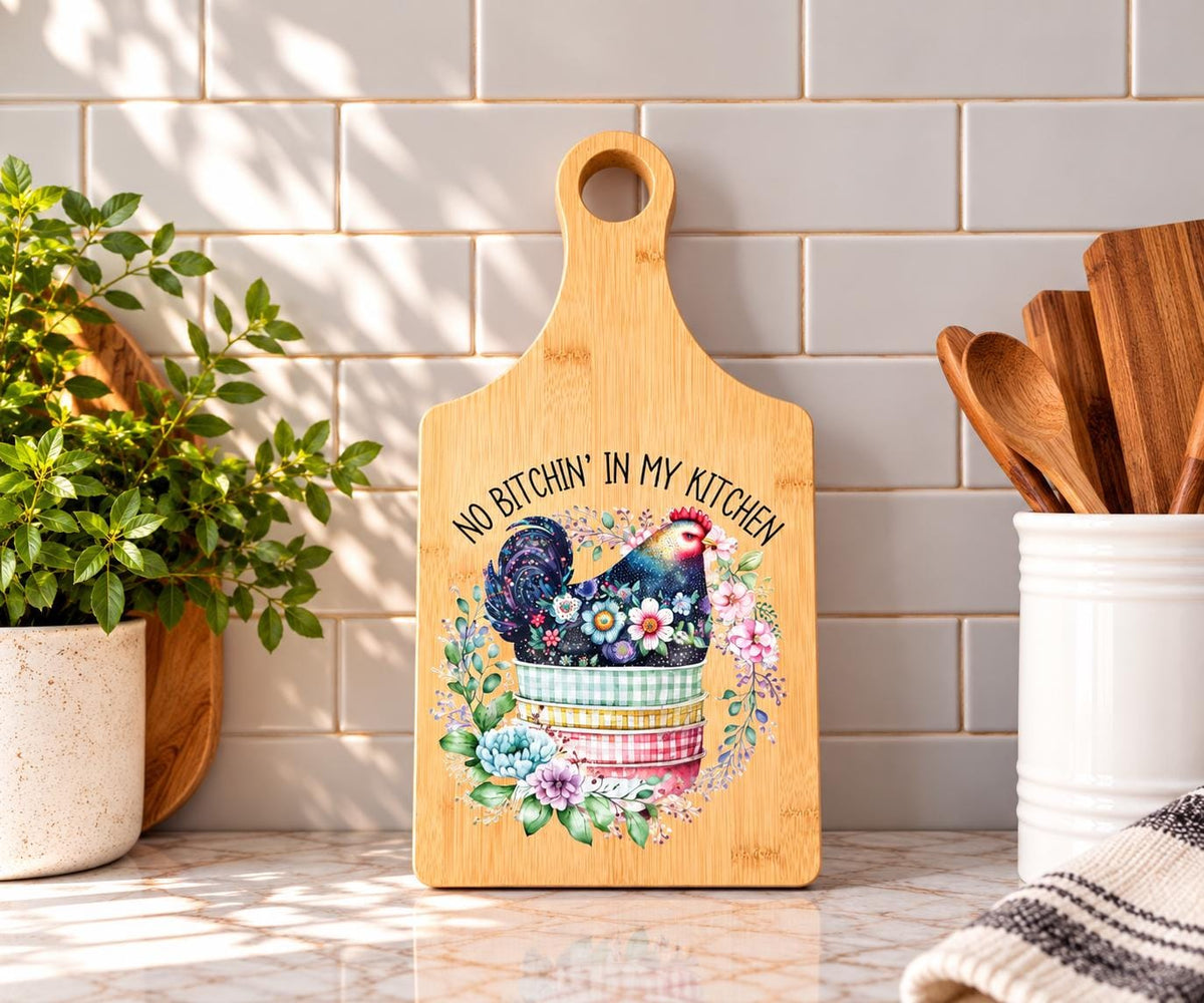Decorative bamboo paddle board with chicken illustration and the words “No Bitchin' in My Kitchen”.