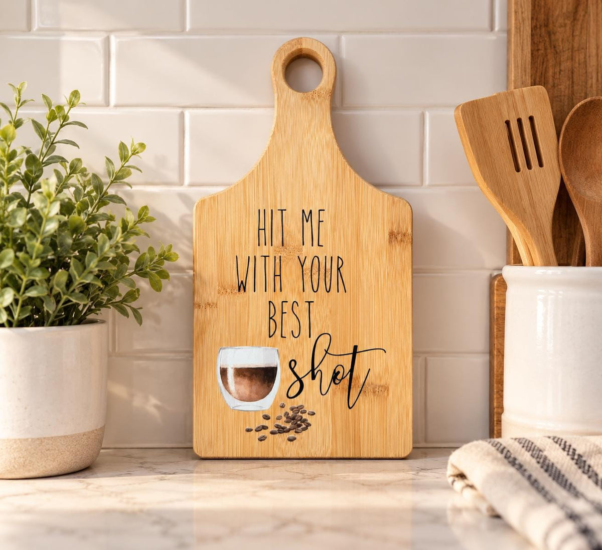 Decorative bamboo paddle board with coffee cup and the words “Hit Me With Your Best Shot”.