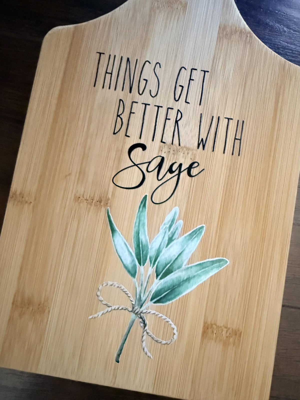 Decorative bamboo paddle board with sage herb sprig and the words “Things Get Better With Sage”.