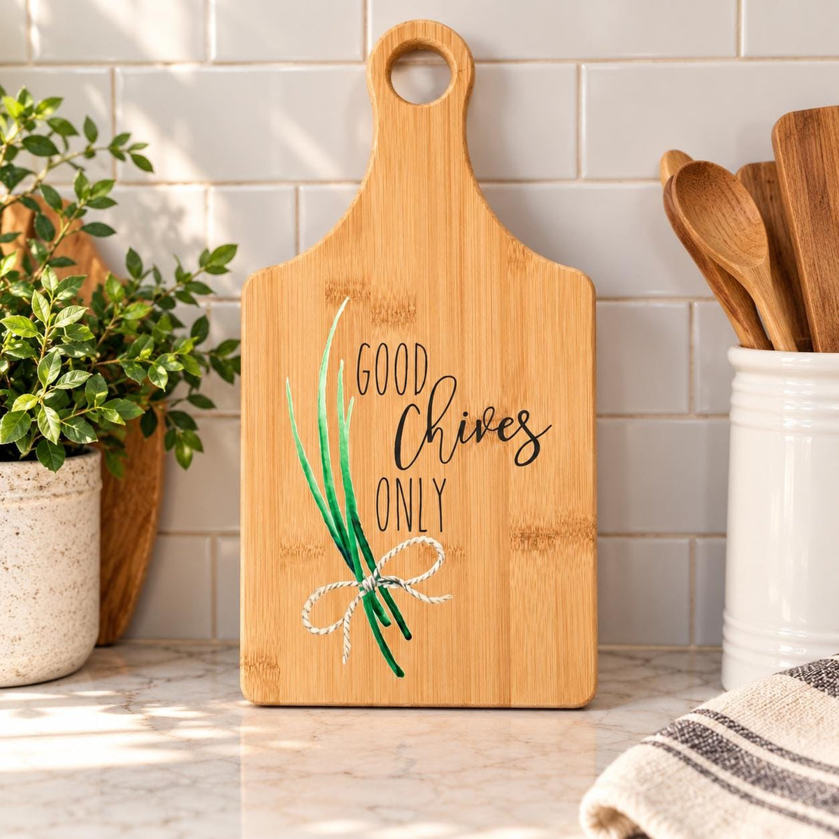 Decorative bamboo paddle board with chive herb illustration and the words “Good Chives Only”.