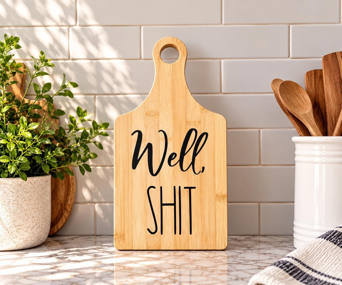 Decorative bamboo paddle board with bold humorous lettering and the words “Well, Shit”.