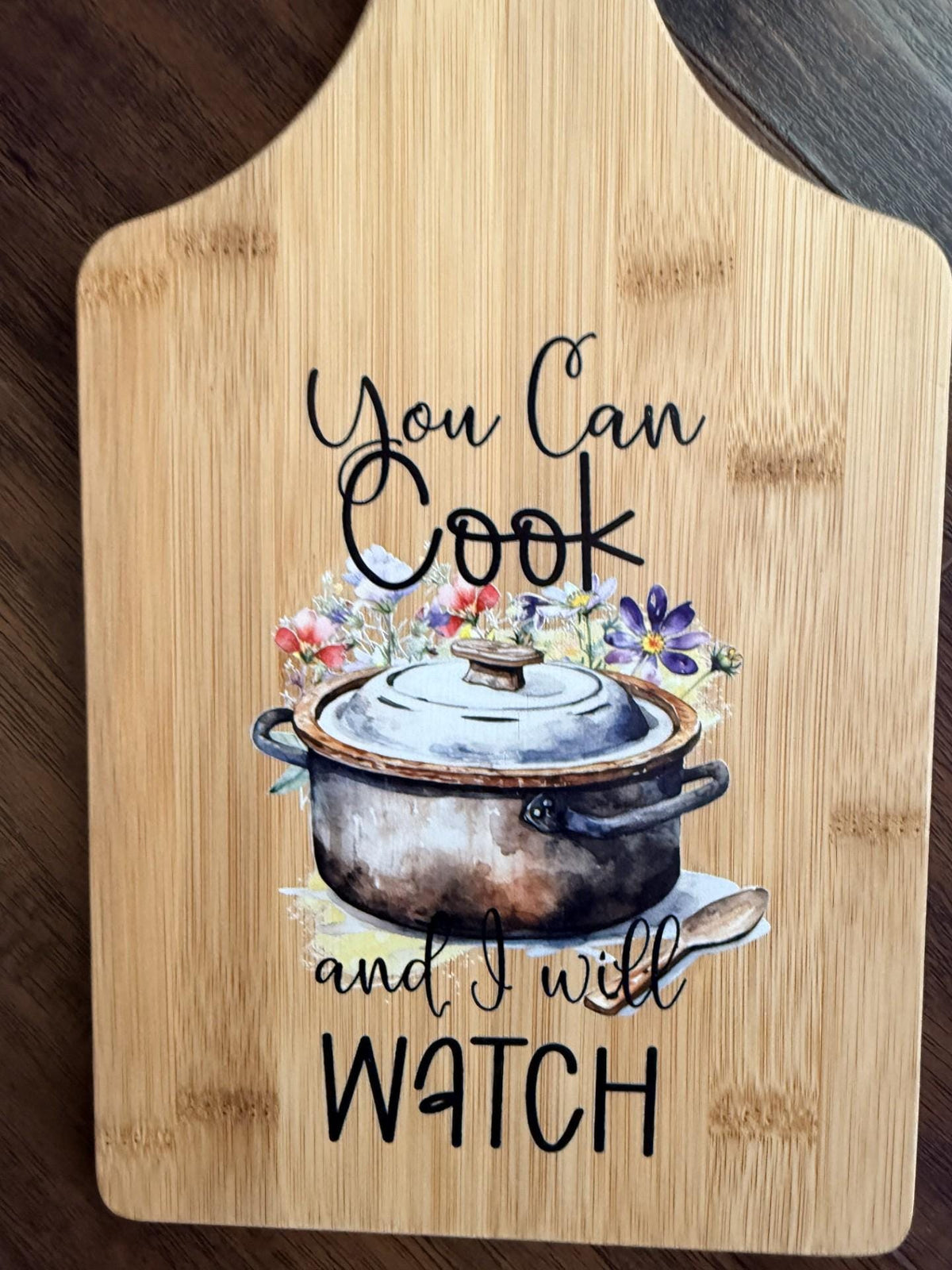 Decorative bamboo paddle board with humorous lettering and the words “You Can Cook and I Will Watch”.