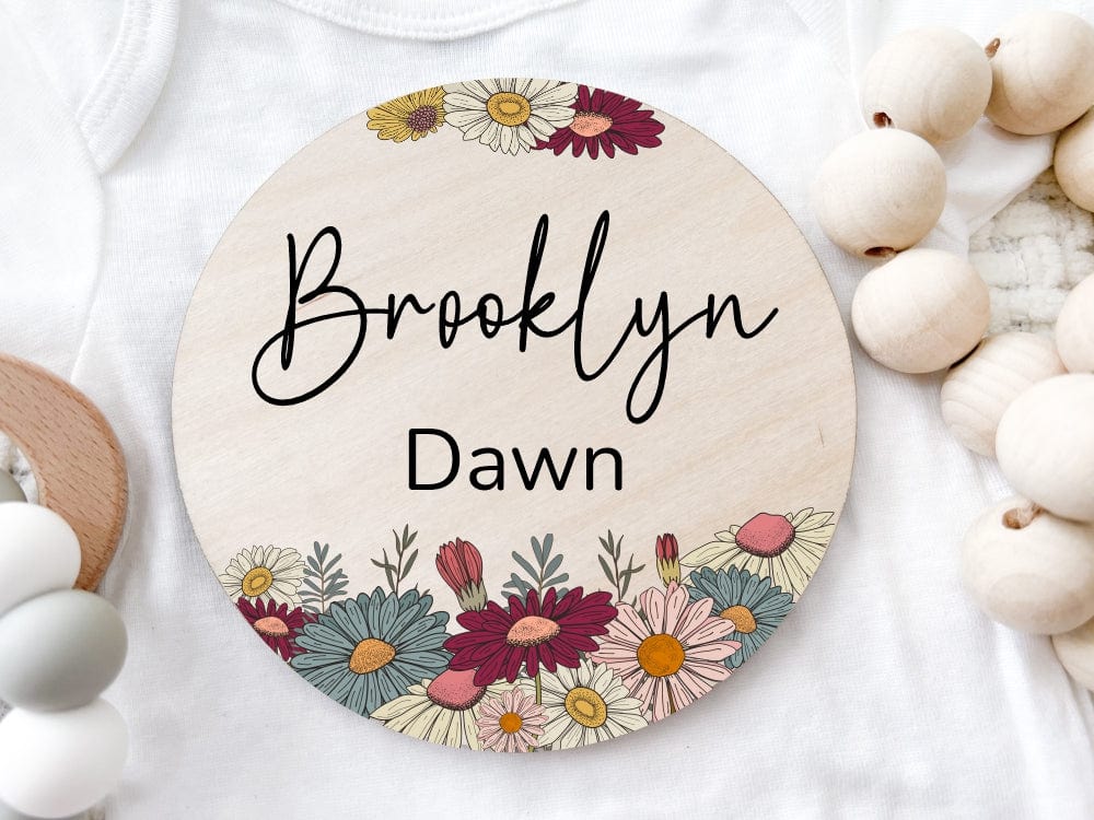 round wood baby name announcement sign printed with colorful daisy flowers in assorted colors