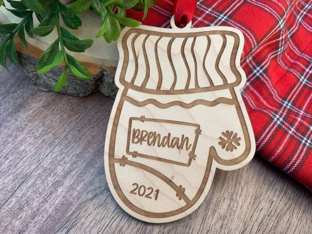 1/4 inch maple plywood Christmas Ornament. laser cut and engraved mitten shape personalized with name and year.